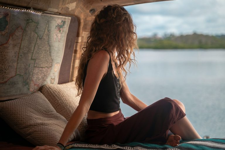 Home 10 Woman wearing black spaghetti strap top sitting viewing body of water